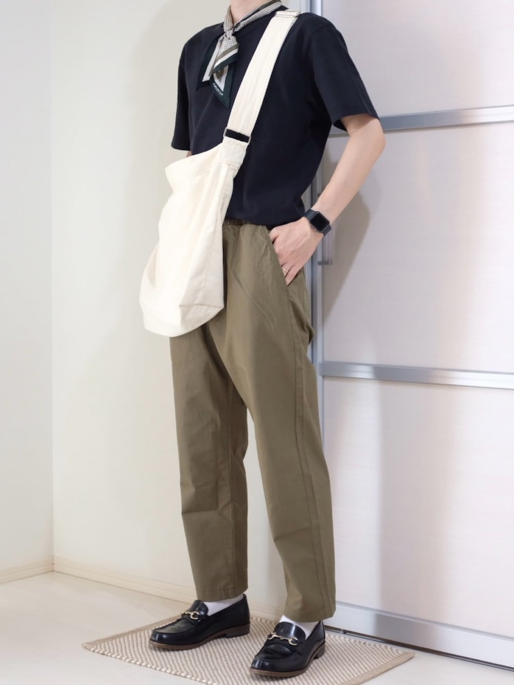 ベージュ系のショルダーバッグ、ブラック系のTシャツ/カットソー、ブラック系のローファーを着用したメンズの秋コーディネートの2枚目の写真