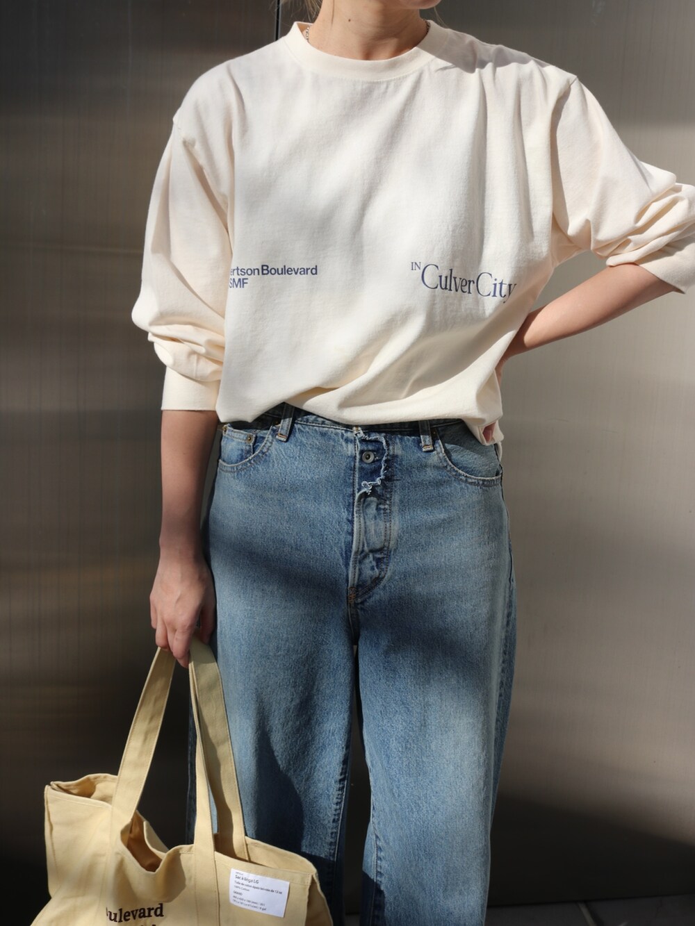 ホワイト系のTシャツ/カットソー、ブルー系のデニムパンツ、イエロー系のトートバッグを着用したレディースの春コーディネートの4枚目の写真