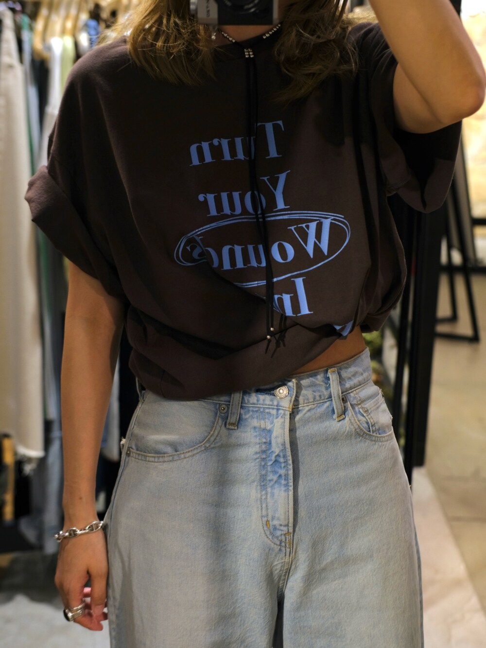 ブルー系のデニムパンツ、ブラウン系のTシャツ/カットソー、ホワイト系のサンダルを着用したレディースの夏コーディネートの2枚目の写真