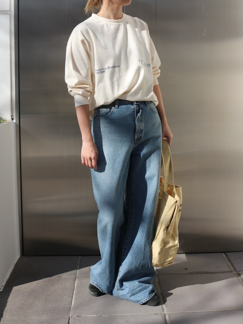 ホワイト系のTシャツ/カットソー、ブルー系のデニムパンツ、イエロー系のトートバッグを着用したレディースの春コーディネートの2枚目の写真