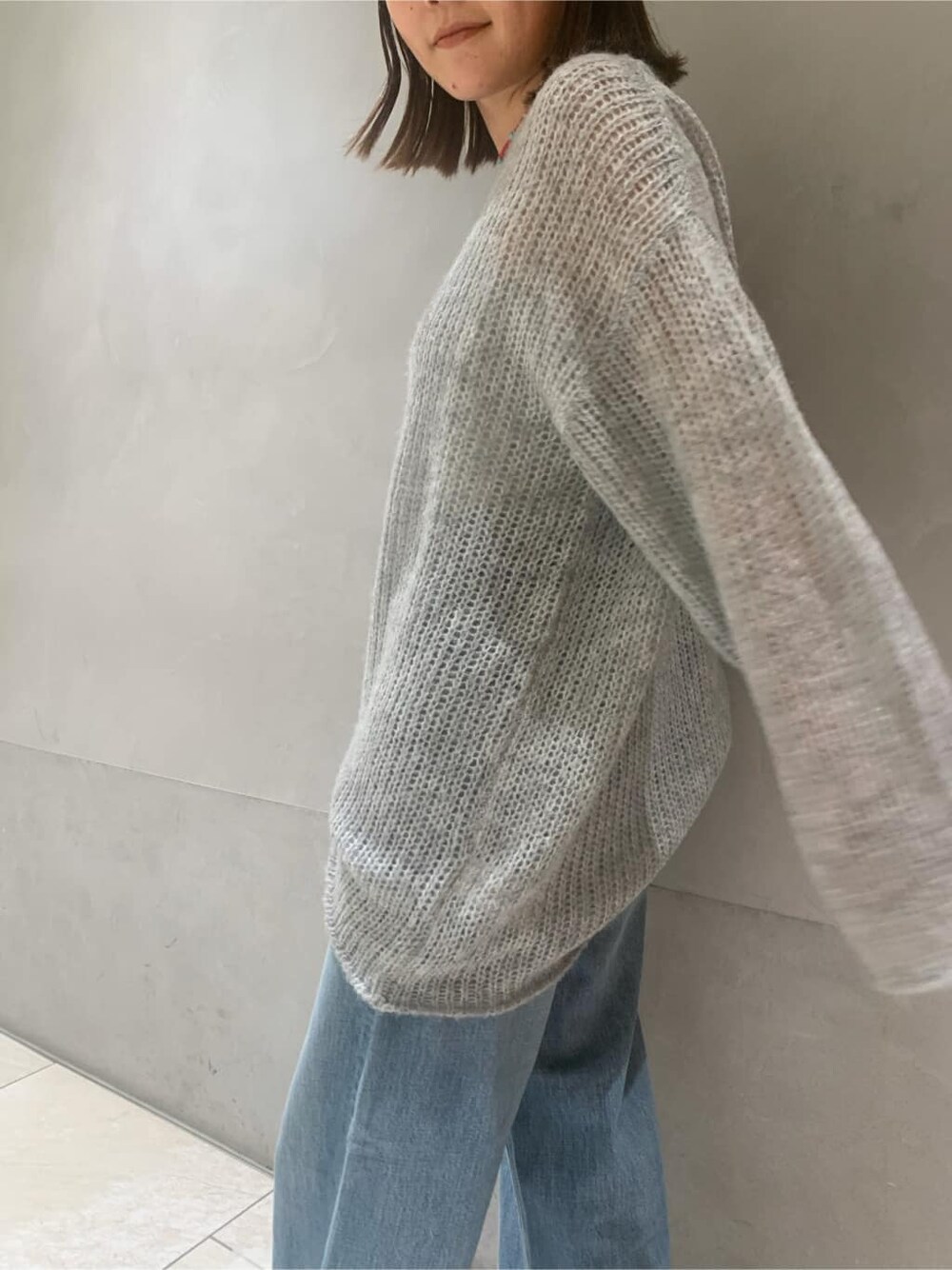 ホワイト系のブーツ、ブルー系のデニムパンツ、グレー系のニット/セーターを着用したレディースの秋コーディネートの4枚目の写真