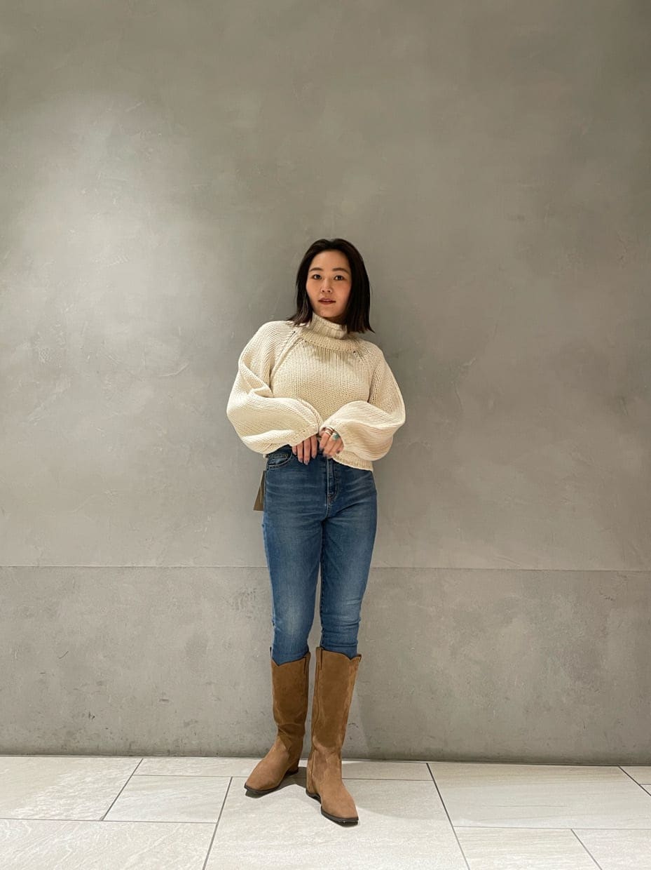 ベージュ系のブーツ、ホワイト系のニット/セーター、ブルー系のデニムパンツを着用したレディースの秋コーディネートの4枚目の写真