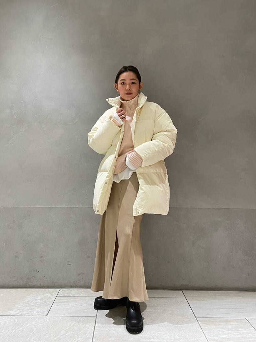 ホワイト系のダウンジャケット/コート、ベージュ系のスカート、ブラック系のブーツを着用したレディースの秋コーディネートの2枚目の写真