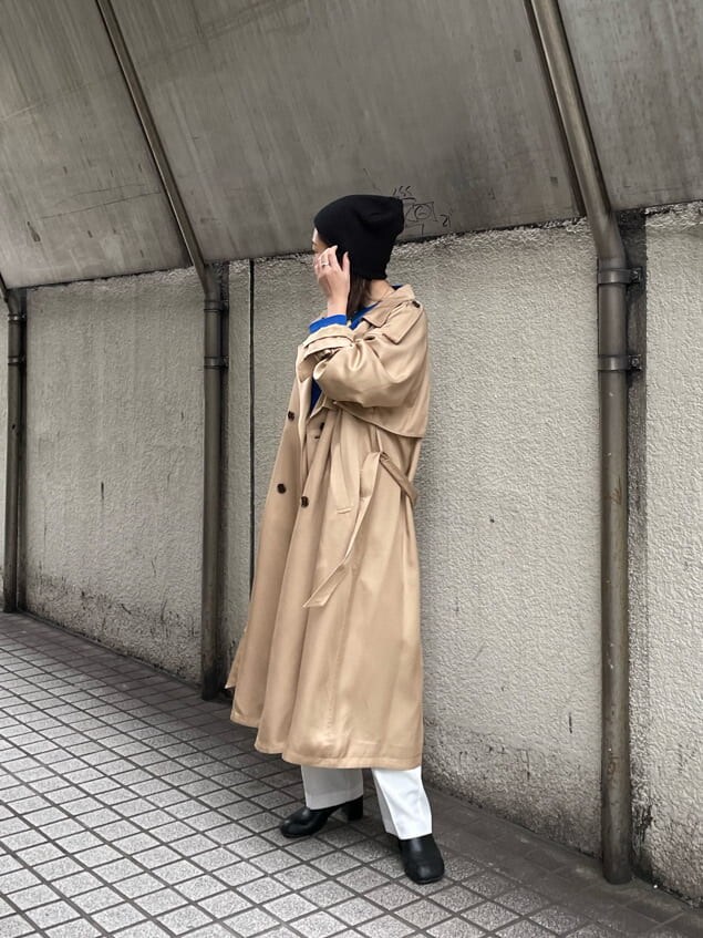 ベージュ系のトレンチコート、ホワイト系のスラックス、ブラック系のハンドバッグを着用したレディースの冬コーディネートの3枚目の写真