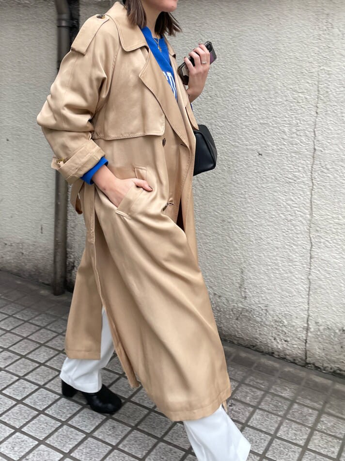 ベージュ系のトレンチコート、ホワイト系のスラックス、ブラック系のハンドバッグを着用したレディースの冬コーディネートの6枚目の写真