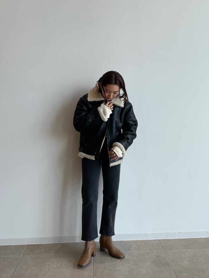 ブラック系のブルゾン、ブラウン系のブーツ、ブラック系のデニムパンツを着用したレディースの秋コーディネートの3枚目の写真