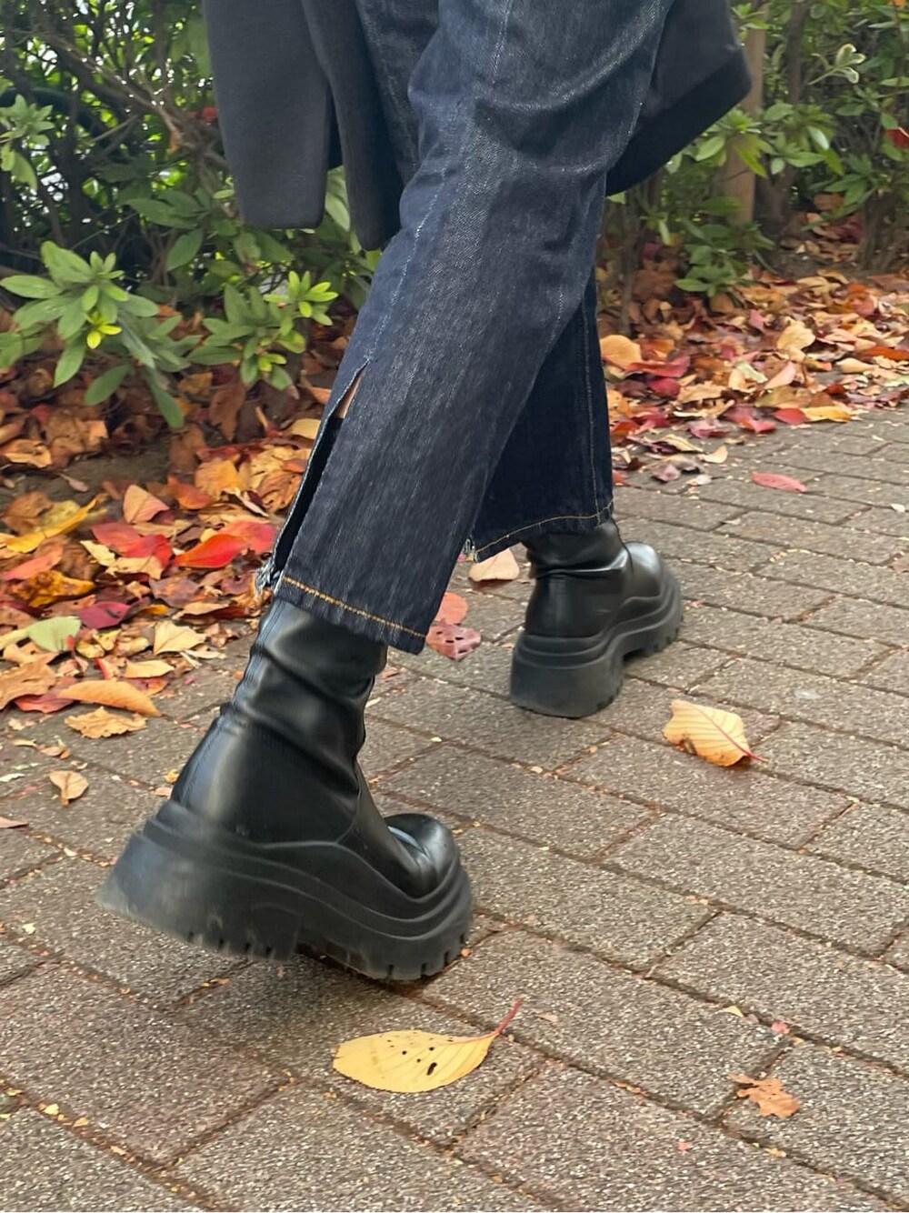 ブルー系のデニムパンツ、ブラック系のチェスターコート、レッド系のニット/セーターを着用したレディースの秋コーディネートの3枚目の写真