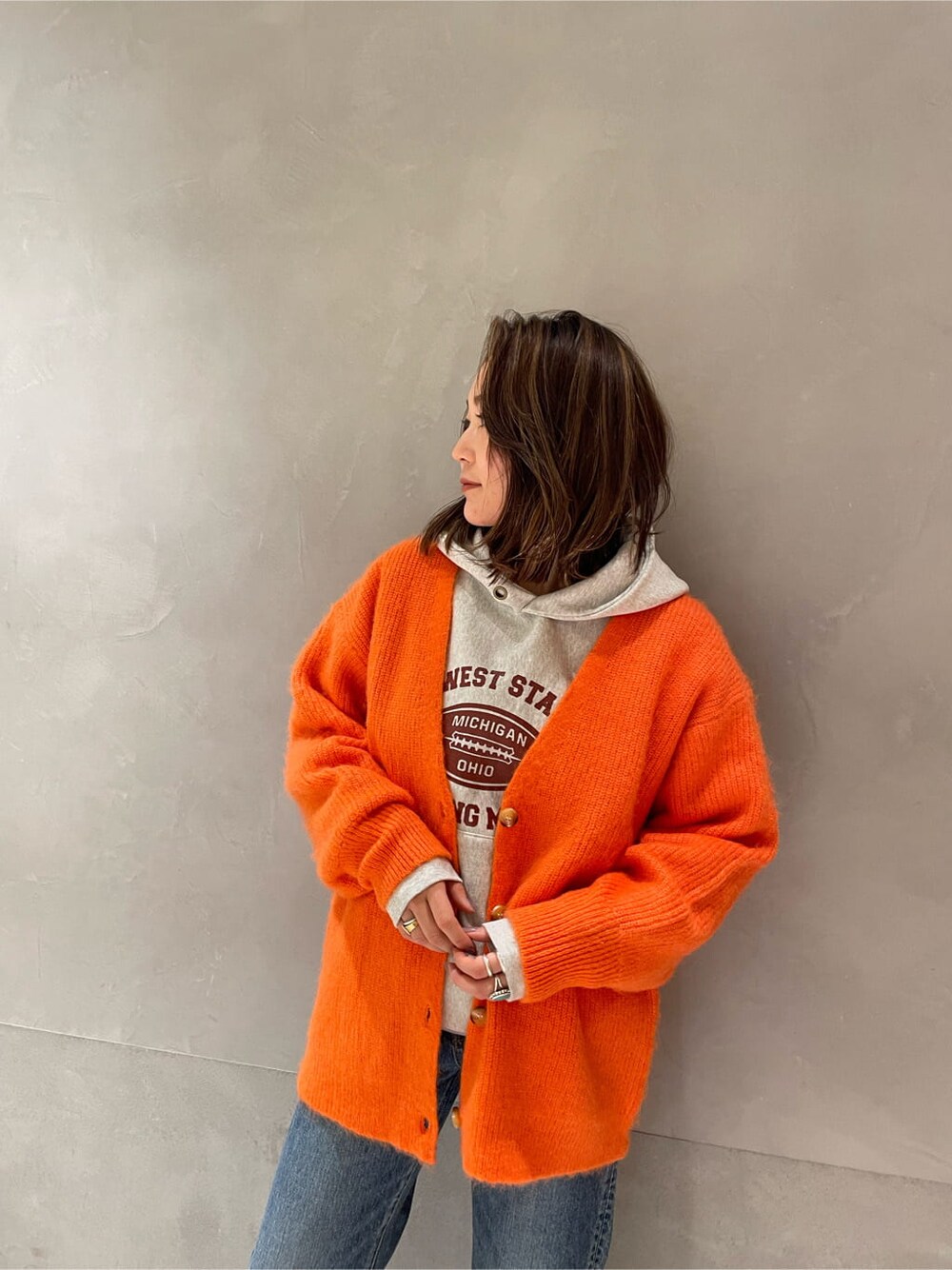 ブルー系のデニムパンツ、グレー系のパーカー、オレンジ系のカーディガン/ボレロを着用したレディースの冬コーディネートの5枚目の写真