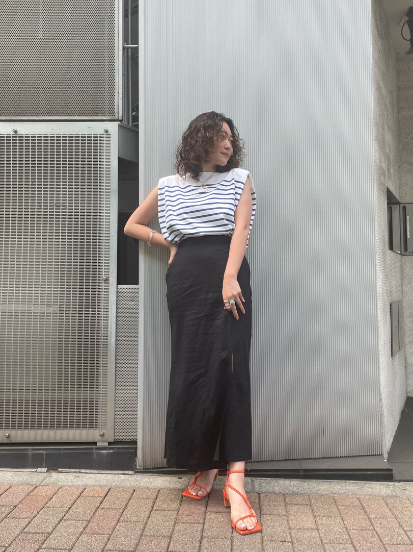 オレンジ系のサンダル、ブラック系のスカートを着用したレディースの春コーディネートの2枚目の写真
