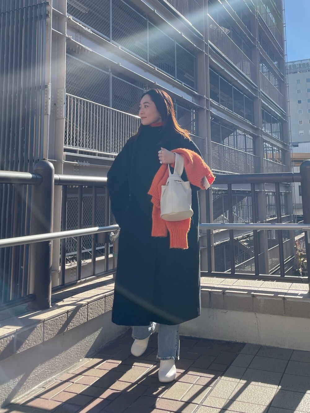 ブルー系のデニムパンツ、レッド系のニット/セーター、オレンジ系のニット/セーターを着用したレディースの冬コーディネートの3枚目の写真