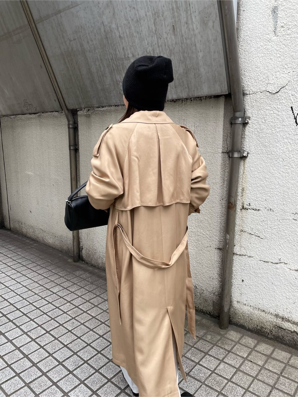 ベージュ系のトレンチコート、ホワイト系のスラックス、ブラック系のハンドバッグを着用したレディースの冬コーディネートの7枚目の写真