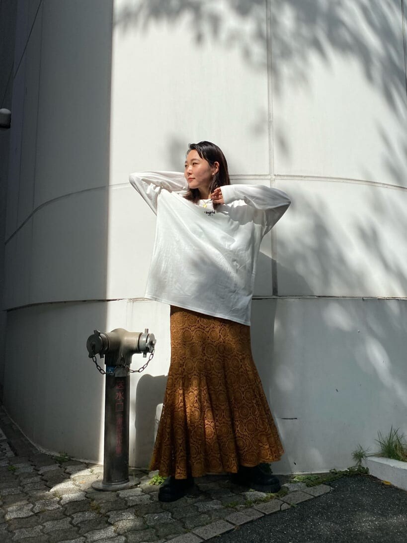 ブラウン系のスカート、ブラック系のブーツ、ホワイト系のTシャツ/カットソーを着用したレディースの夏コーディネートの4枚目の写真