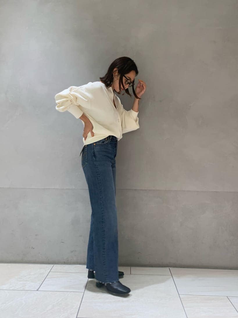 ブラック系のブーツ、ブルー系のデニムパンツ、ホワイト系のカーディガン/ボレロを着用したレディースの秋コーディネートの2枚目の写真