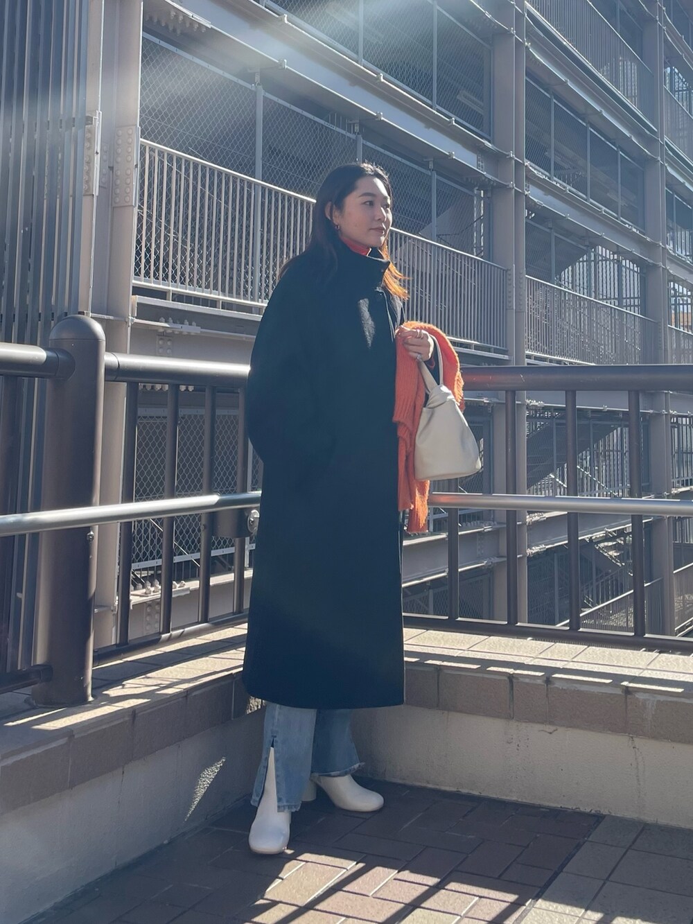 ブルー系のデニムパンツ、レッド系のニット/セーター、オレンジ系のニット/セーターを着用したレディースの冬コーディネートの4枚目の写真