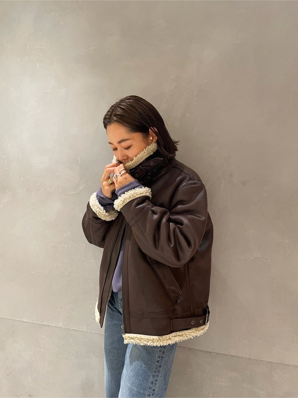 ブラウン系のブルゾン、ブルー系のデニムパンツ、ブルー系のスウェットを着用したレディースの秋コーディネートの2枚目の写真