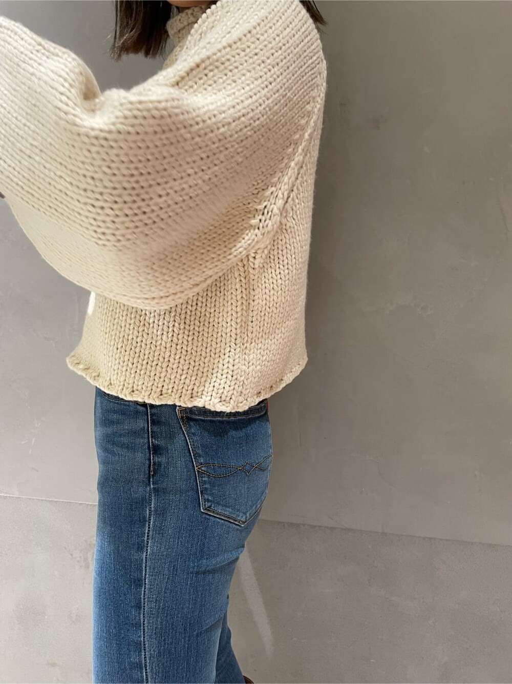 ベージュ系のブーツ、ホワイト系のニット/セーター、ブルー系のデニムパンツを着用したレディースの秋コーディネートの6枚目の写真