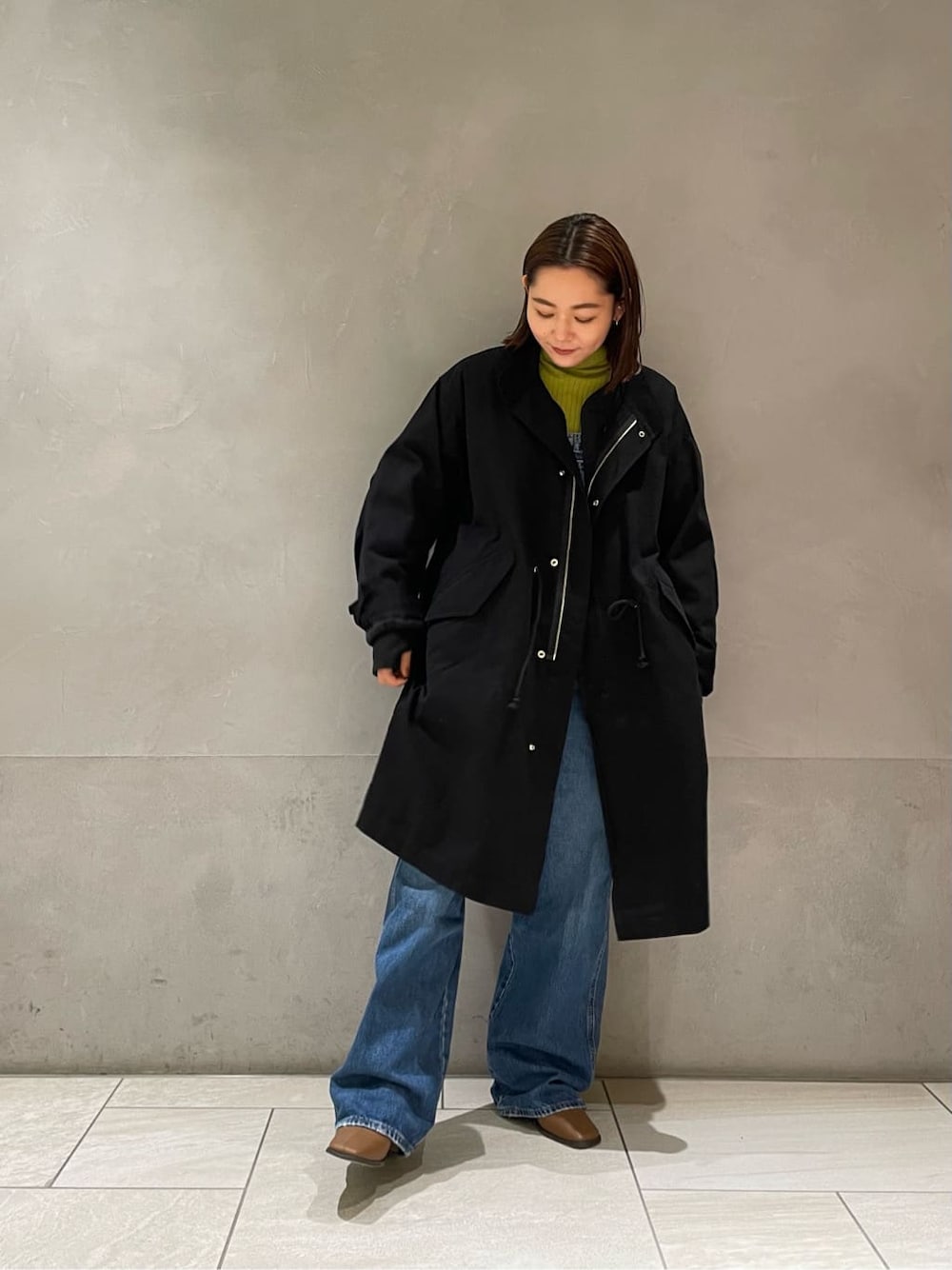 ブルー系のサロペット/オーバーオール、グリーン系のニット/セーター、ブラック系のその他アウターを着用したレディースの秋コーディネートの2枚目の写真