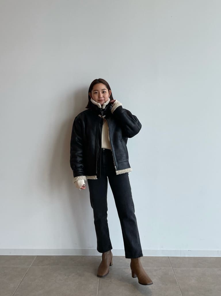 ブラック系のブルゾン、ブラウン系のブーツ、ブラック系のデニムパンツを着用したレディースの秋コーディネートの2枚目の写真