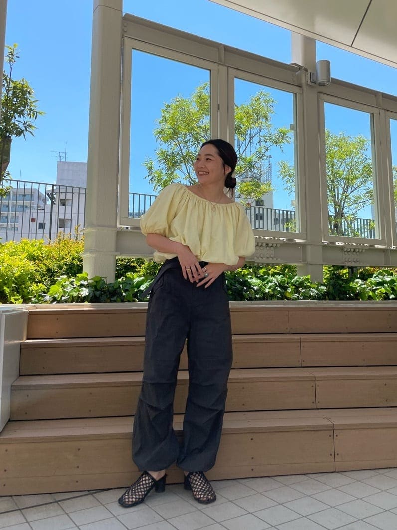 イエロー系のシャツ/ブラウス、ブラック系のサンダル、グレー系のその他パンツを着用したレディースの春コーディネートの2枚目の写真