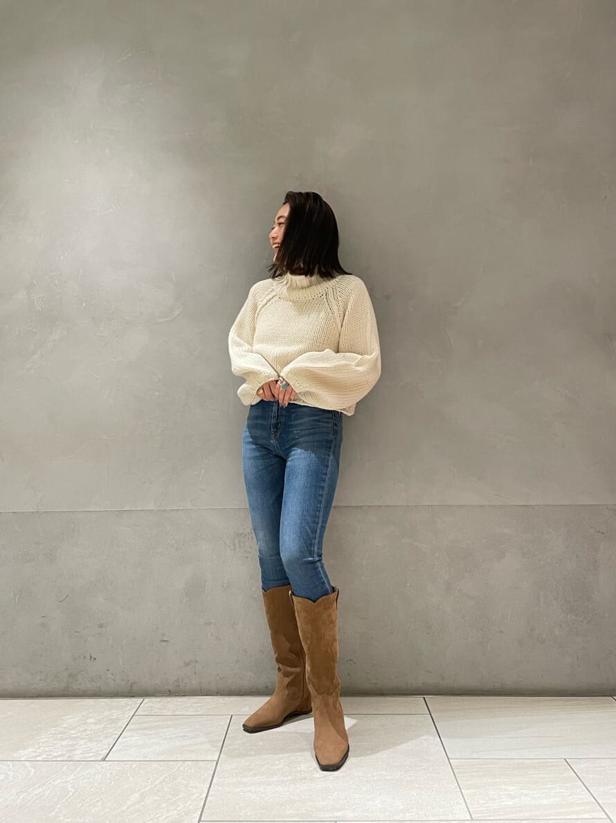 ベージュ系のブーツ、ホワイト系のニット/セーター、ブルー系のデニムパンツを着用したレディースの秋コーディネートの3枚目の写真