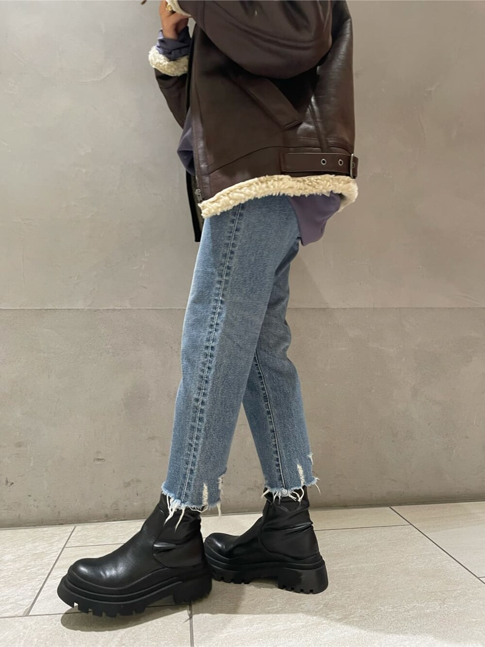 ブラウン系のブルゾン、ブルー系のデニムパンツ、ブルー系のスウェットを着用したレディースの秋コーディネートの6枚目の写真