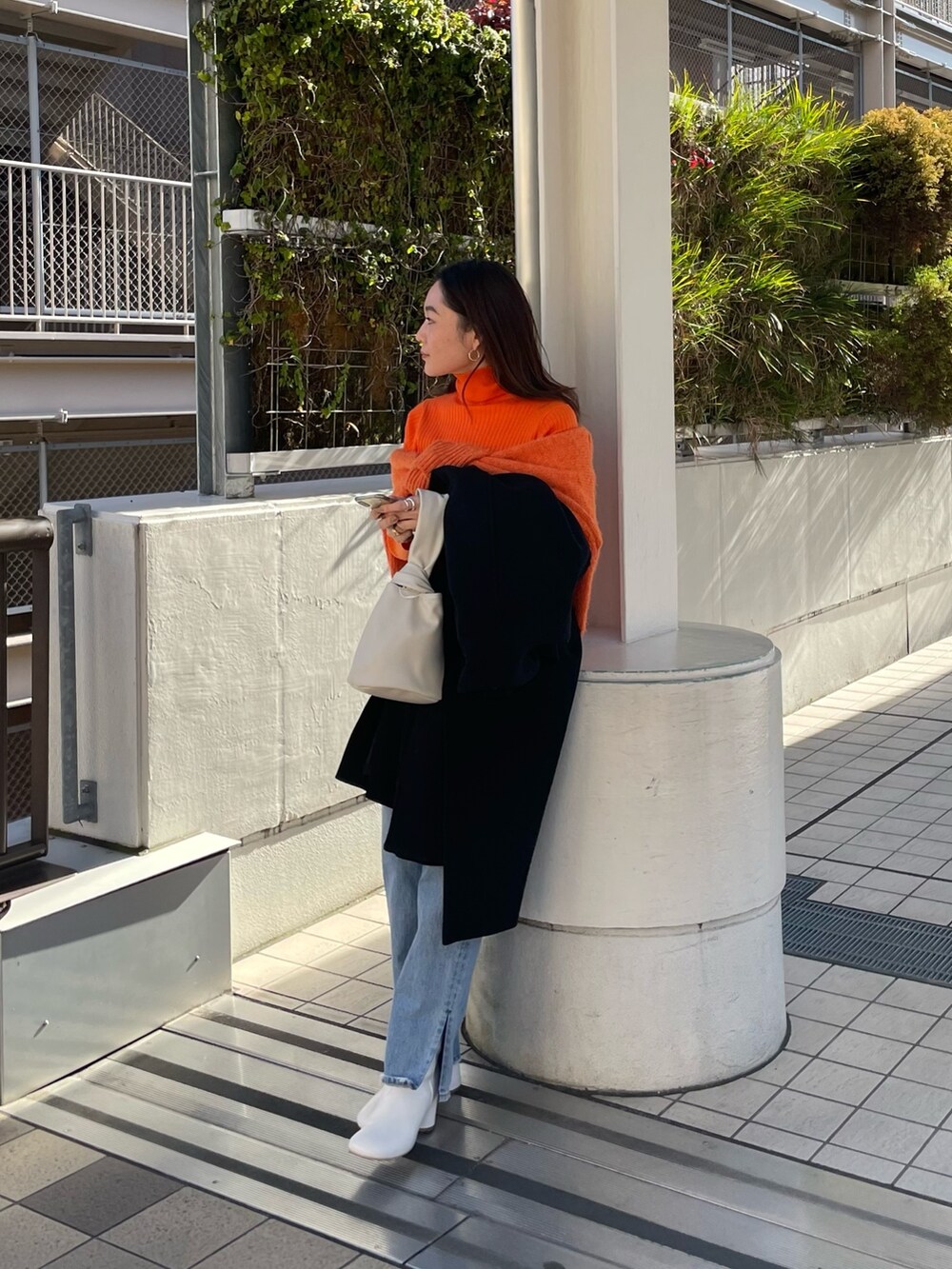 ブルー系のデニムパンツ、レッド系のニット/セーター、オレンジ系のニット/セーターを着用したレディースの冬コーディネートの2枚目の写真