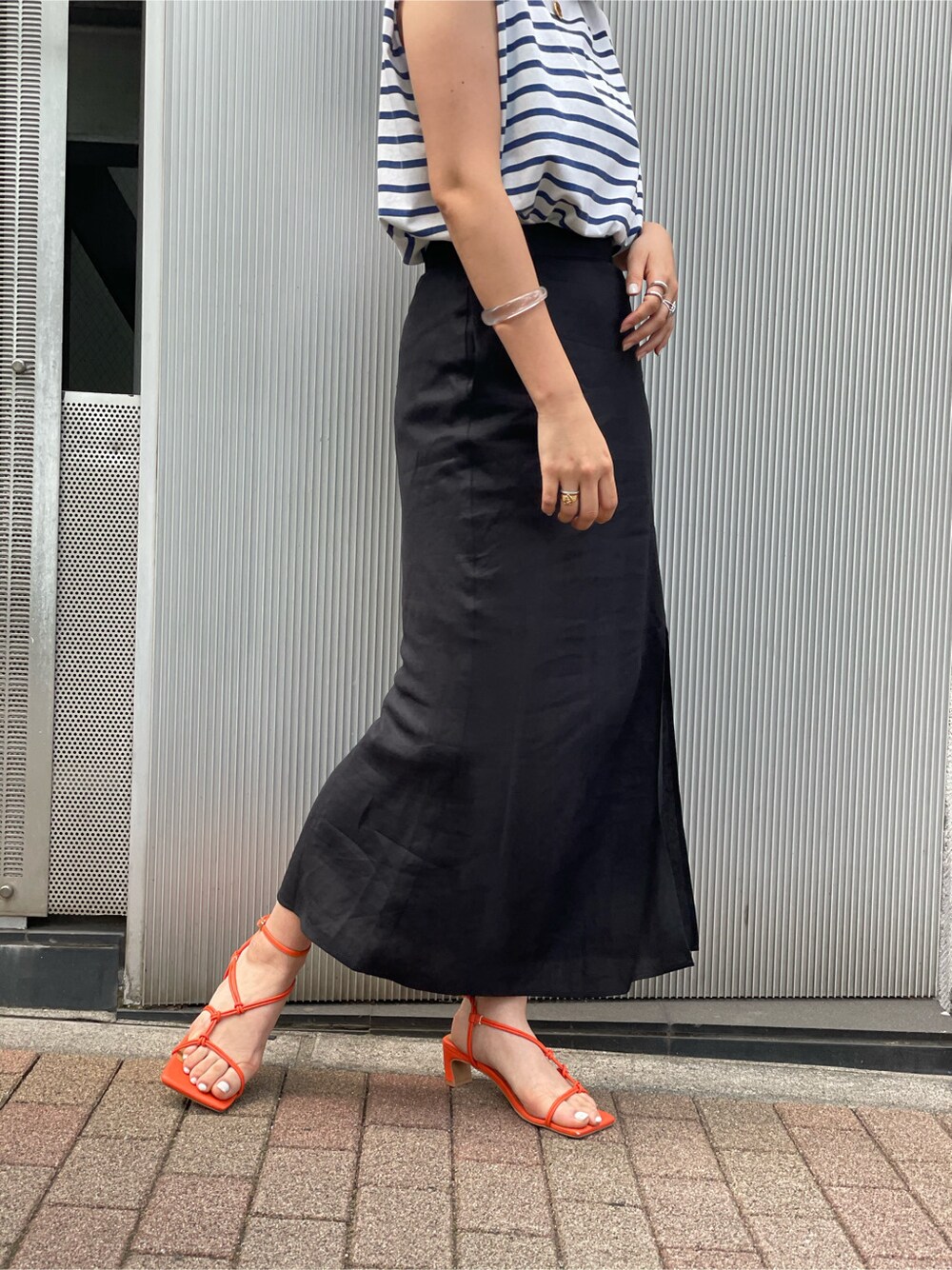 オレンジ系のサンダル、ブラック系のスカートを着用したレディースの春コーディネートの5枚目の写真