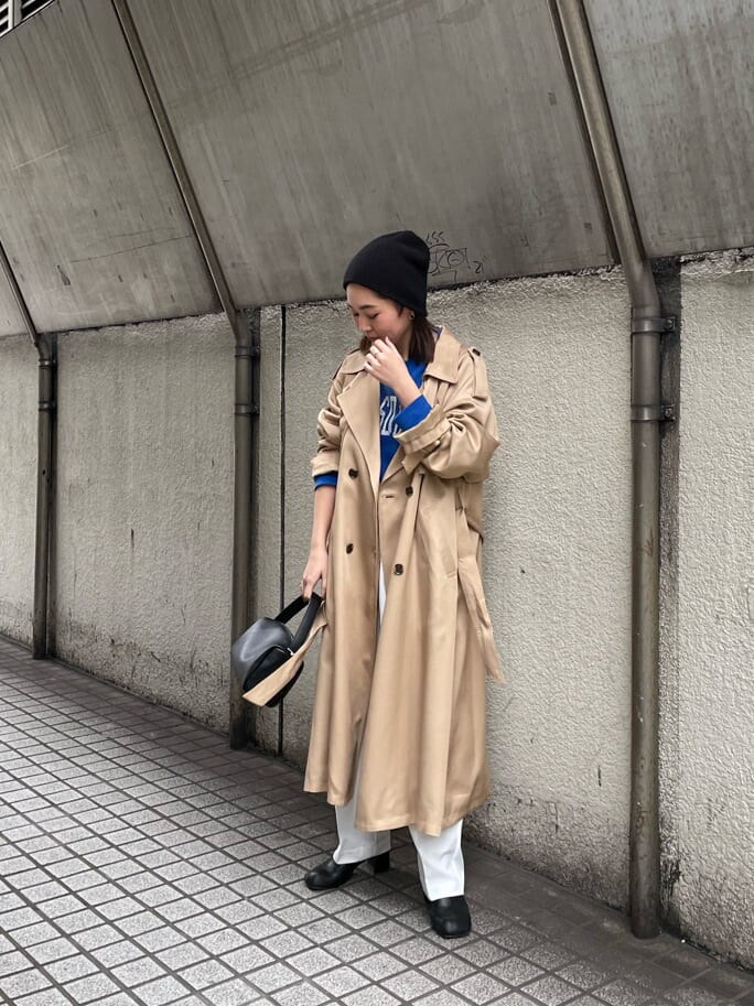 ベージュ系のトレンチコート、ホワイト系のスラックス、ブラック系のハンドバッグを着用したレディースの冬コーディネートの2枚目の写真