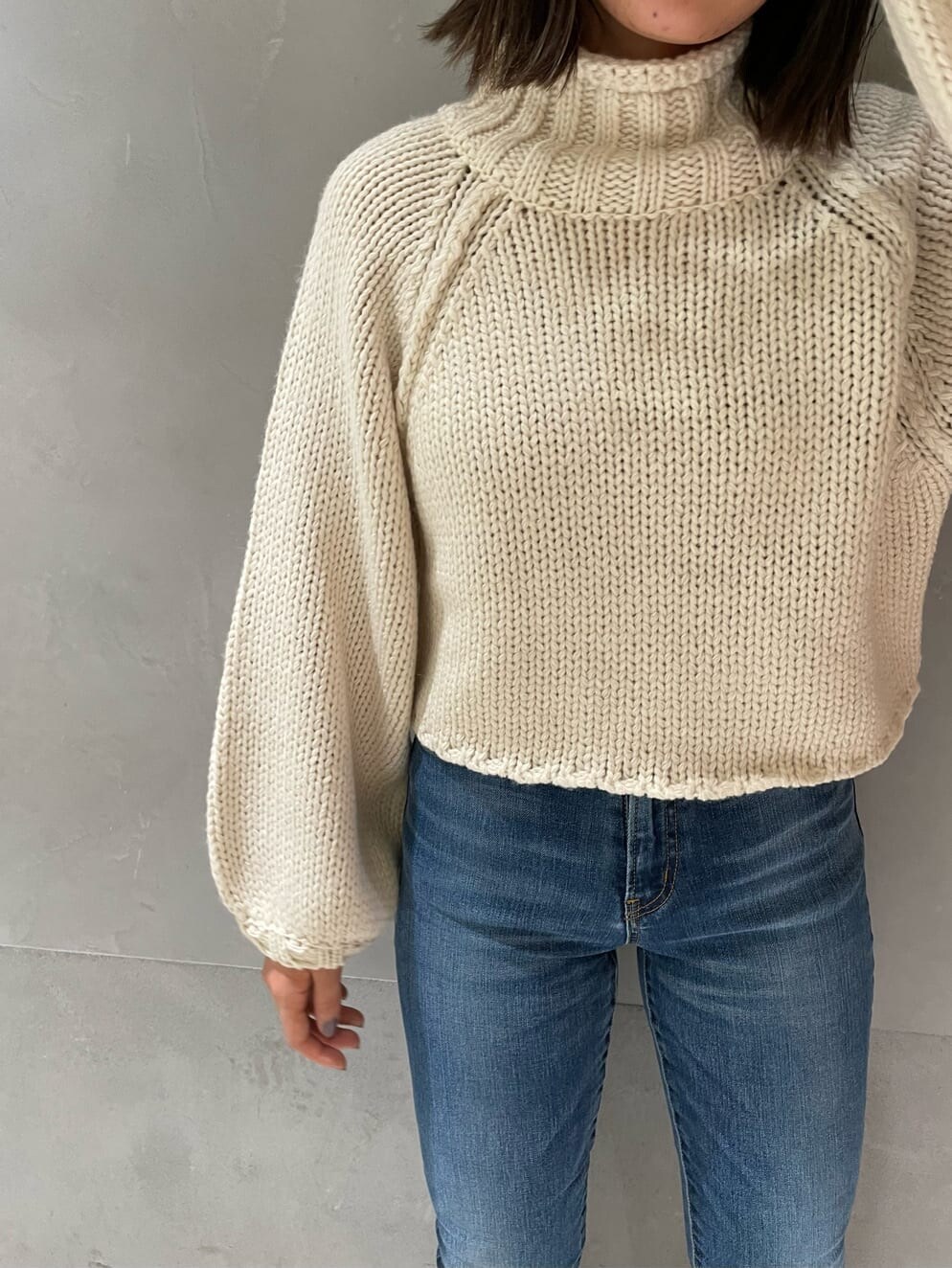 ベージュ系のブーツ、ホワイト系のニット/セーター、ブルー系のデニムパンツを着用したレディースの秋コーディネートの5枚目の写真