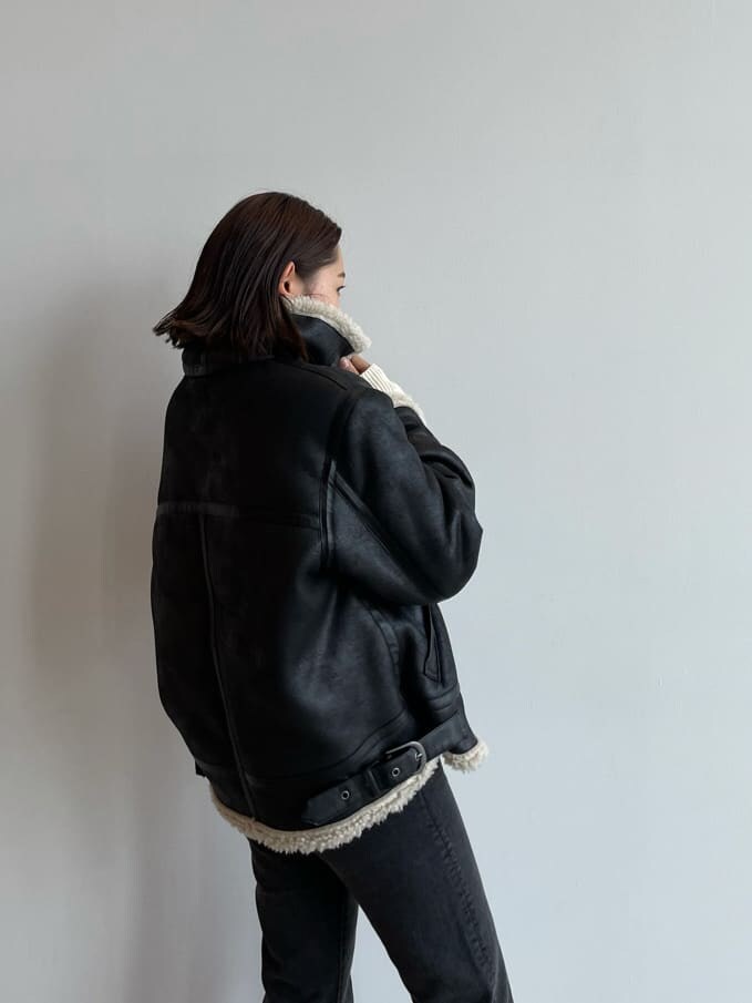 ブラック系のブルゾン、ブラウン系のブーツ、ブラック系のデニムパンツを着用したレディースの秋コーディネートの6枚目の写真