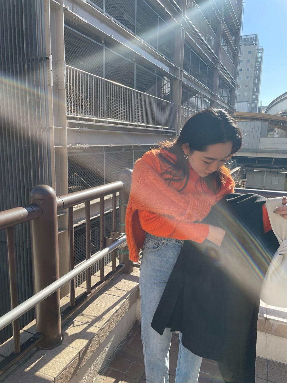 ブルー系のデニムパンツ、レッド系のニット/セーター、オレンジ系のニット/セーターを着用したレディースの冬コーディネートの5枚目の写真