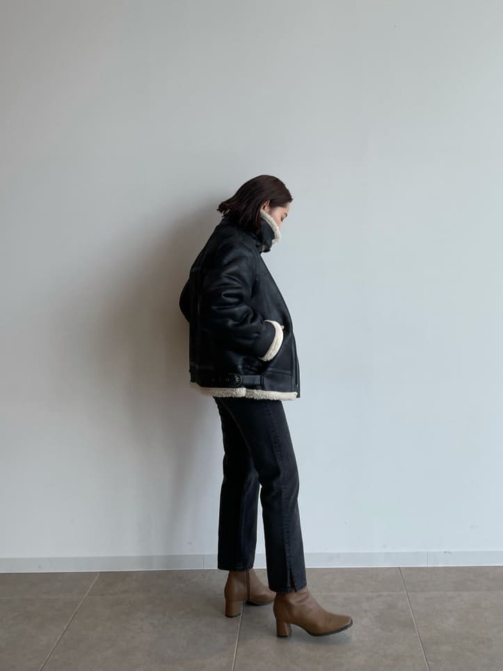 ブラック系のブルゾン、ブラウン系のブーツ、ブラック系のデニムパンツを着用したレディースの秋コーディネートの5枚目の写真