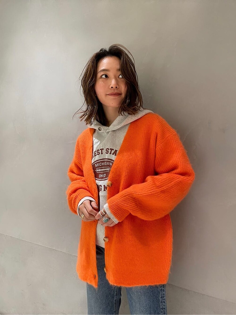 ブルー系のデニムパンツ、グレー系のパーカー、オレンジ系のカーディガン/ボレロを着用したレディースの冬コーディネートの6枚目の写真