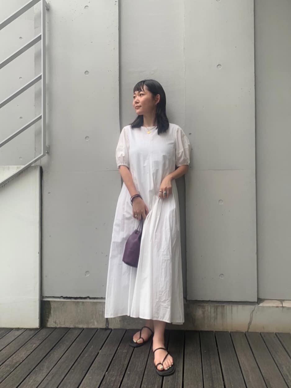 ホワイト系のワンピース、ブラック系のサンダル、パープル系のハンドバッグを着用したレディースの夏コーディネートの2枚目の写真