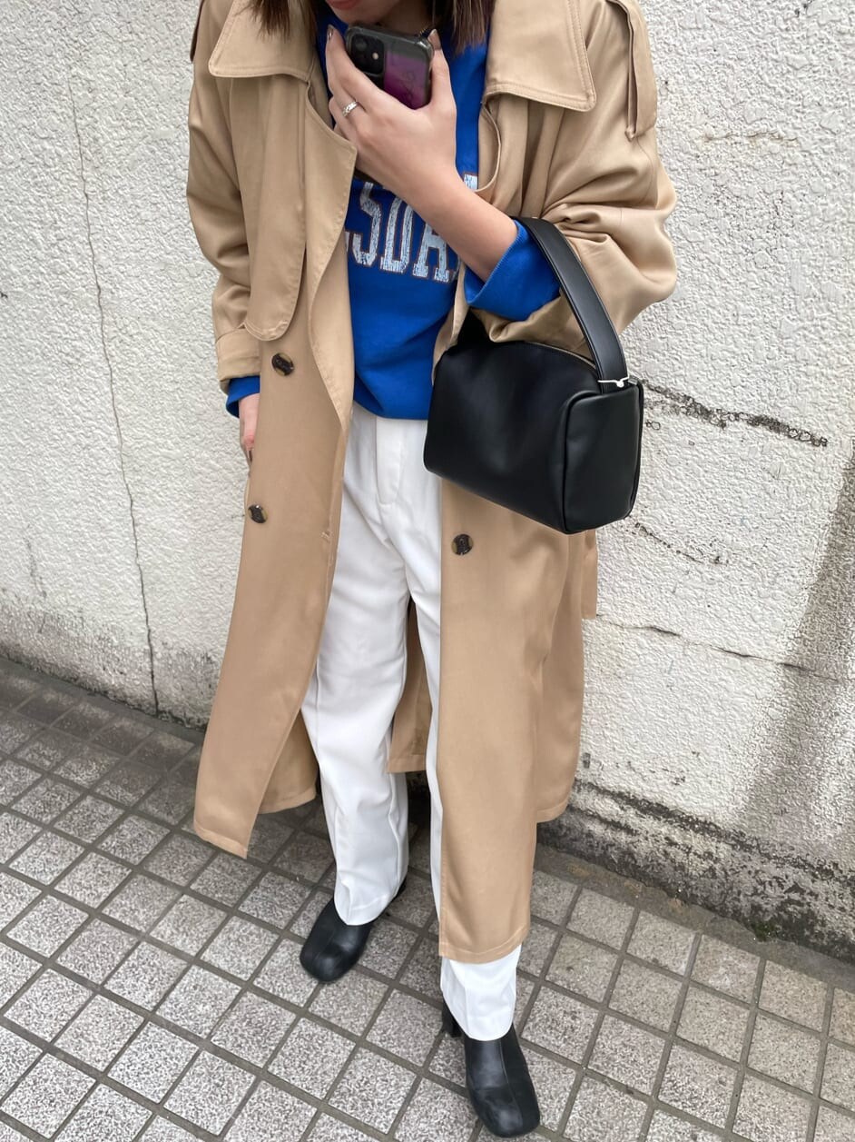 ベージュ系のトレンチコート、ホワイト系のスラックス、ブラック系のハンドバッグを着用したレディースの冬コーディネートの4枚目の写真