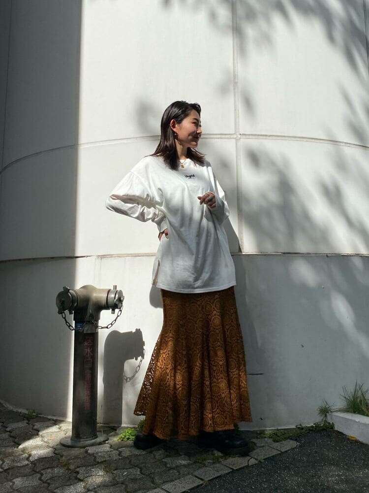 ブラウン系のスカート、ブラック系のブーツ、ホワイト系のTシャツ/カットソーを着用したレディースの夏コーディネートの2枚目の写真