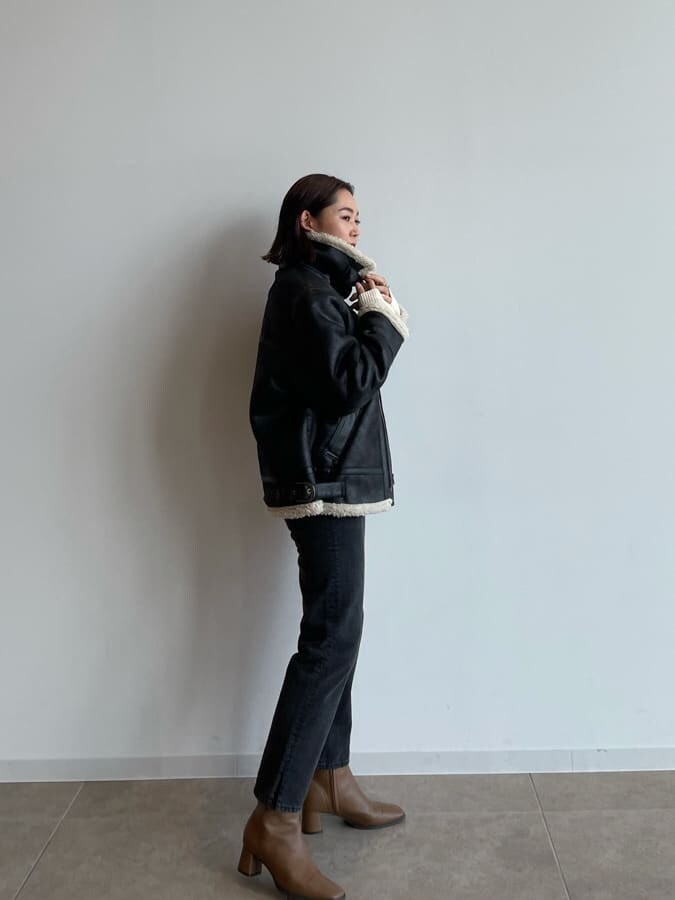 ブラック系のブルゾン、ブラウン系のブーツ、ブラック系のデニムパンツを着用したレディースの秋コーディネートの4枚目の写真