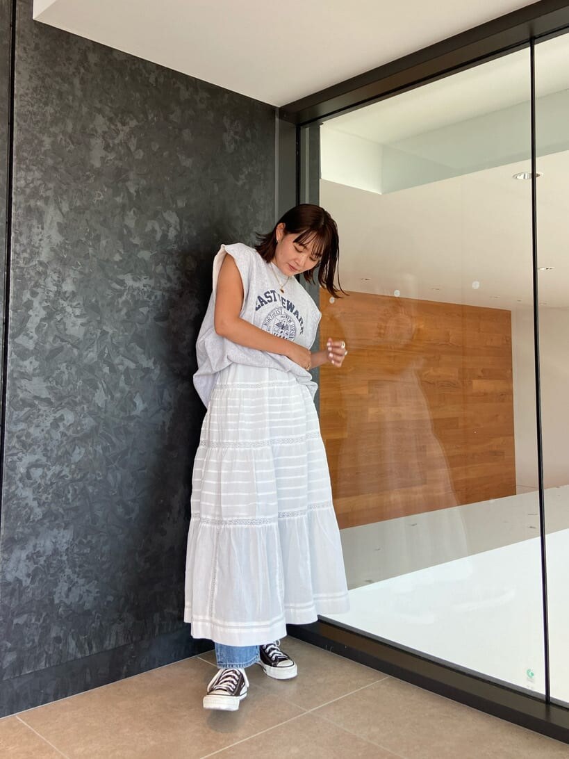 ブルー系のデニムパンツ、ブルー系のタンクトップ、ホワイト系のスカートを着用したレディースの夏コーディネートの2枚目の写真