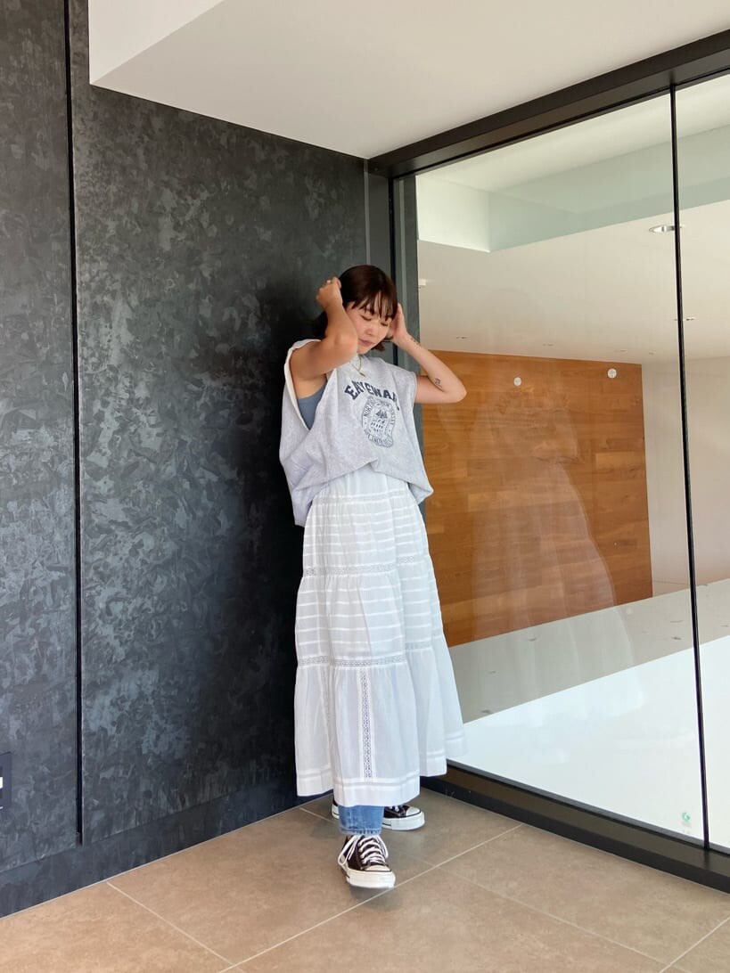 ブルー系のデニムパンツ、ブルー系のタンクトップ、ホワイト系のスカートを着用したレディースの夏コーディネートの3枚目の写真