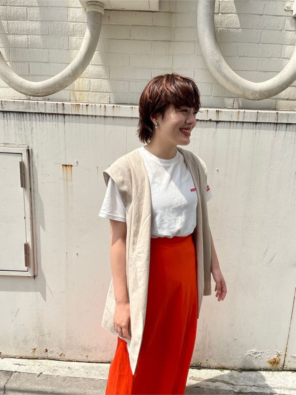 ホワイト系のベスト、ホワイト系のTシャツ/カットソー、オレンジ系のスカートを着用したレディースの夏コーディネートの3枚目の写真