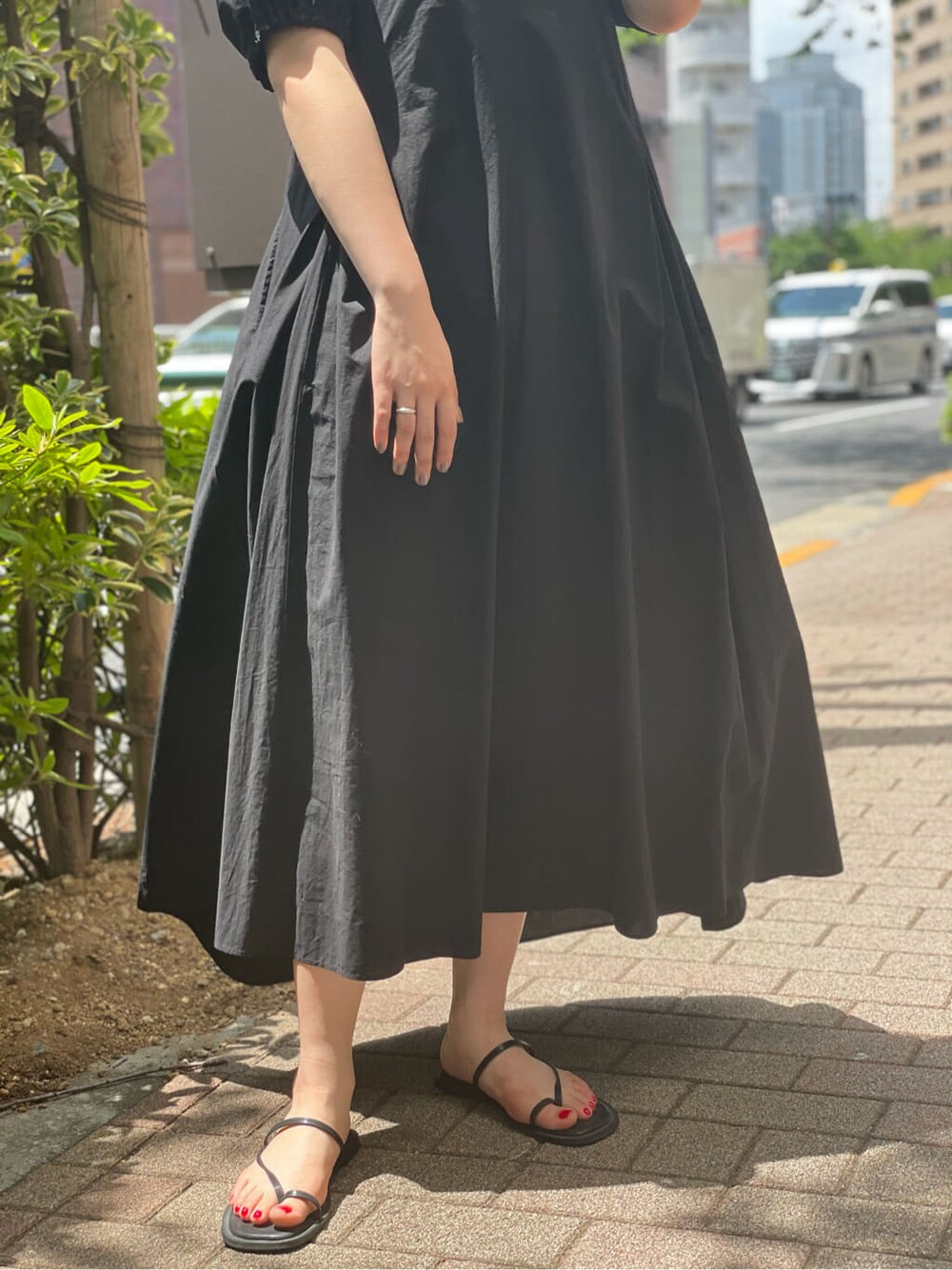 ブラック系のワンピース、ブラック系のサンダル、オレンジ系のストール/ショールを着用したレディースの夏コーディネートの4枚目の写真