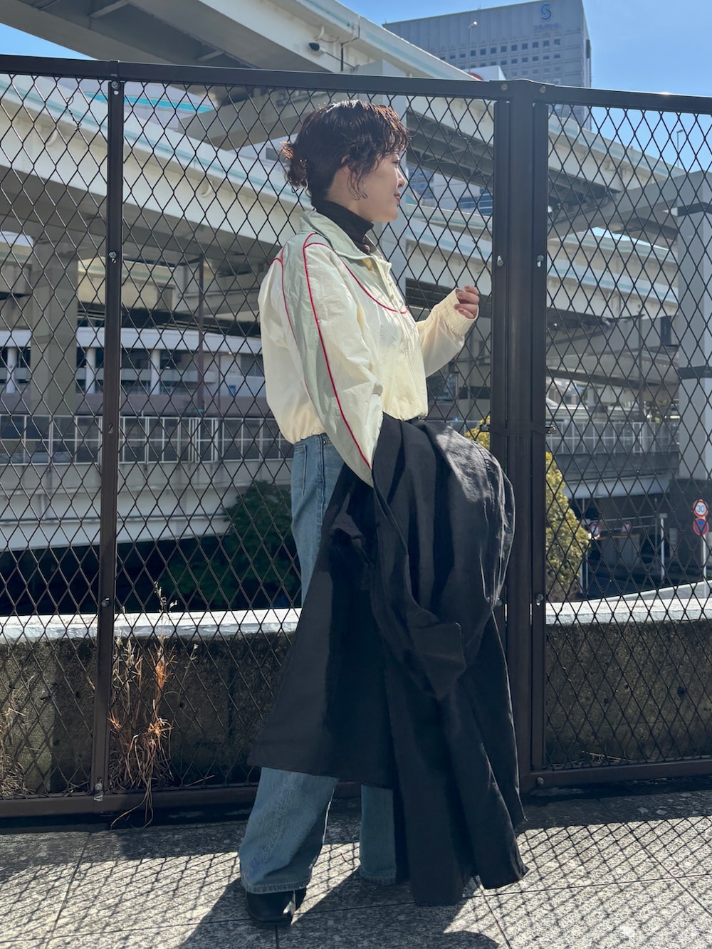 ブラック系のステンカラーコート、ホワイト系のブルゾンを着用したレディースの冬コーディネートの4枚目の写真