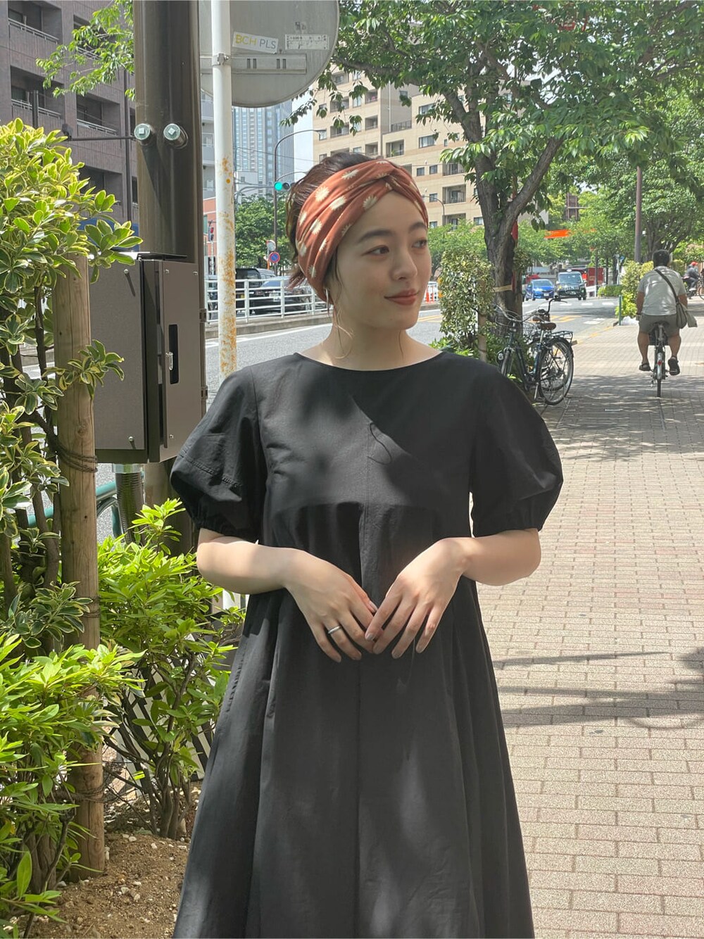 ブラック系のワンピース、ブラック系のサンダル、オレンジ系のストール/ショールを着用したレディースの夏コーディネートの2枚目の写真