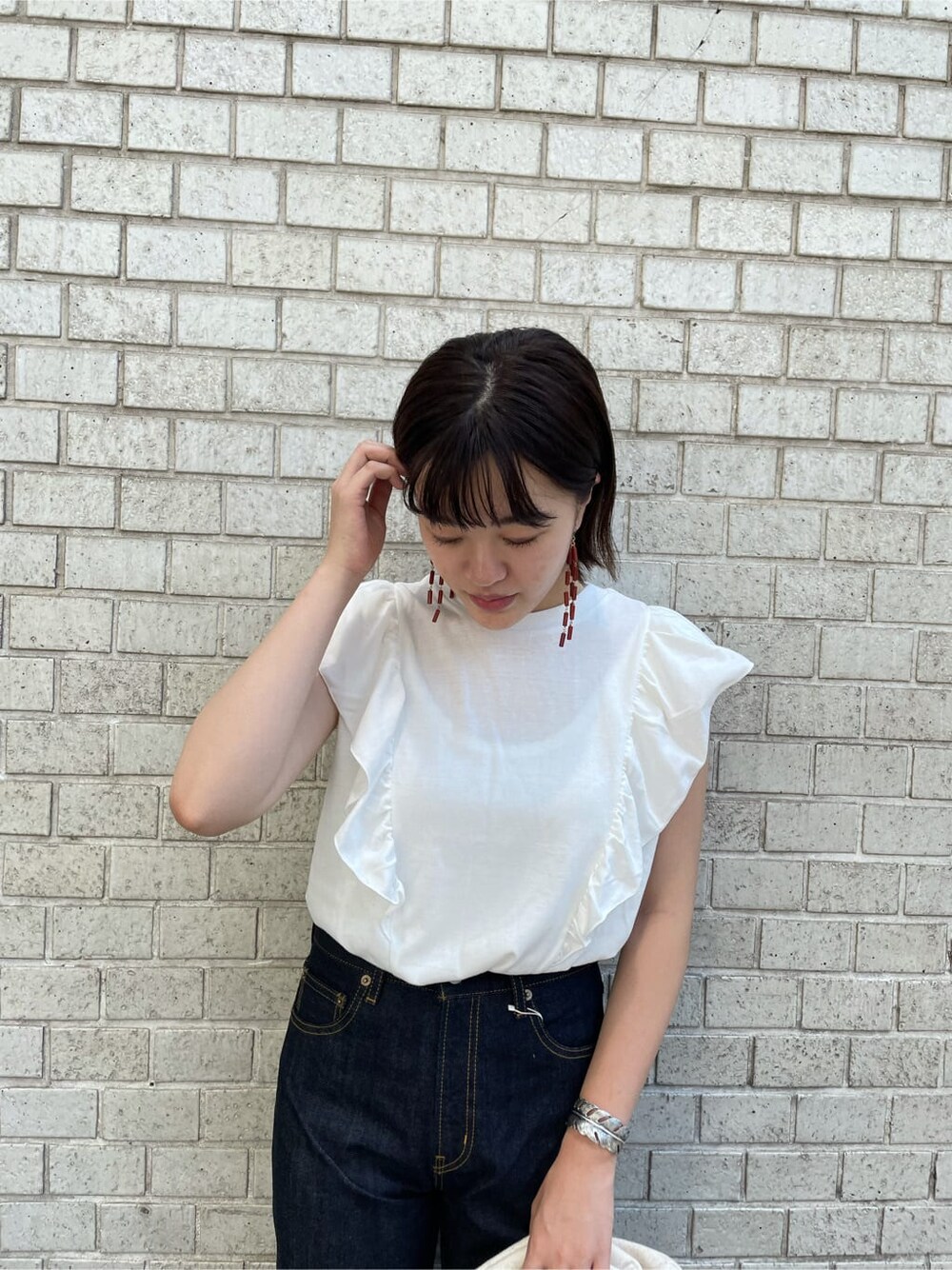 ブルー系のデニムパンツ、ホワイト系のクラッチバッグ、ホワイト系のTシャツ/カットソーを着用したレディースの夏コーディネートの4枚目の写真