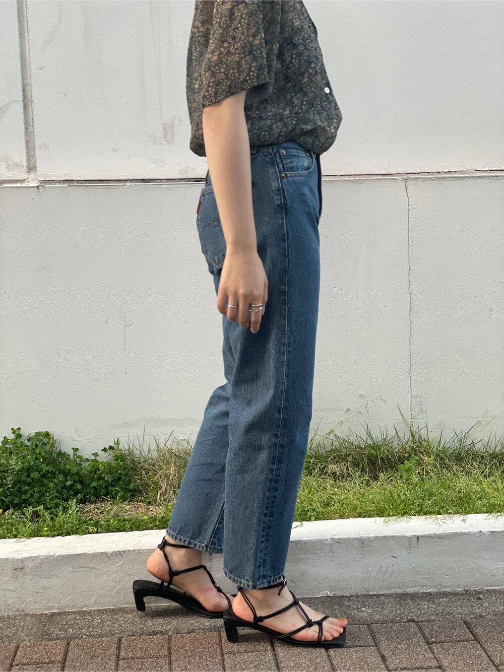 ブルー系のデニムパンツ、レッド系のシャツ/ブラウス、ブラック系のサンダルを着用したレディースの春コーディネートの3枚目の写真