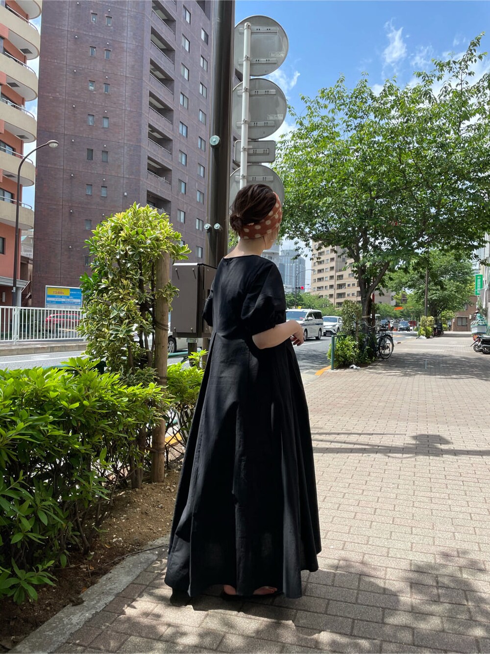 ブラック系のワンピース、ブラック系のサンダル、オレンジ系のストール/ショールを着用したレディースの夏コーディネートの3枚目の写真