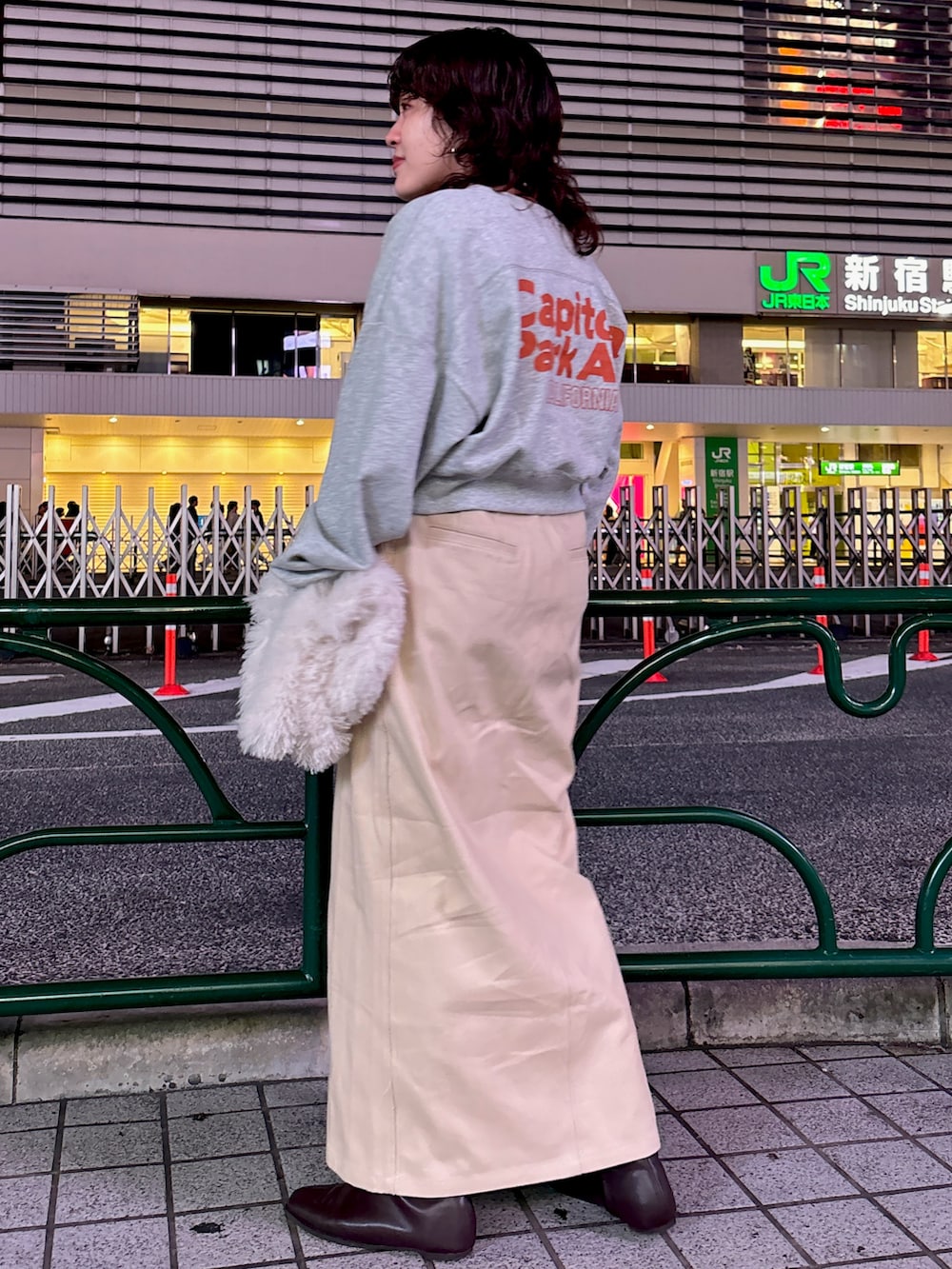 グレー系のスウェット、ベージュ系のスカート、ホワイト系のハンドバッグを着用したレディースの秋コーディネートの3枚目の写真