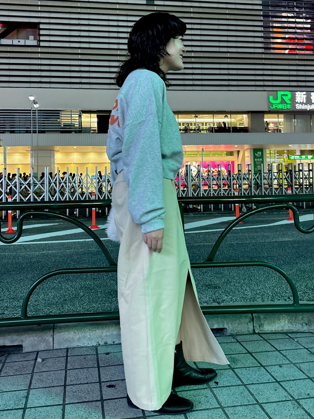 グレー系のスウェット、ベージュ系のスカート、ホワイト系のハンドバッグを着用したレディースの秋コーディネートの2枚目の写真