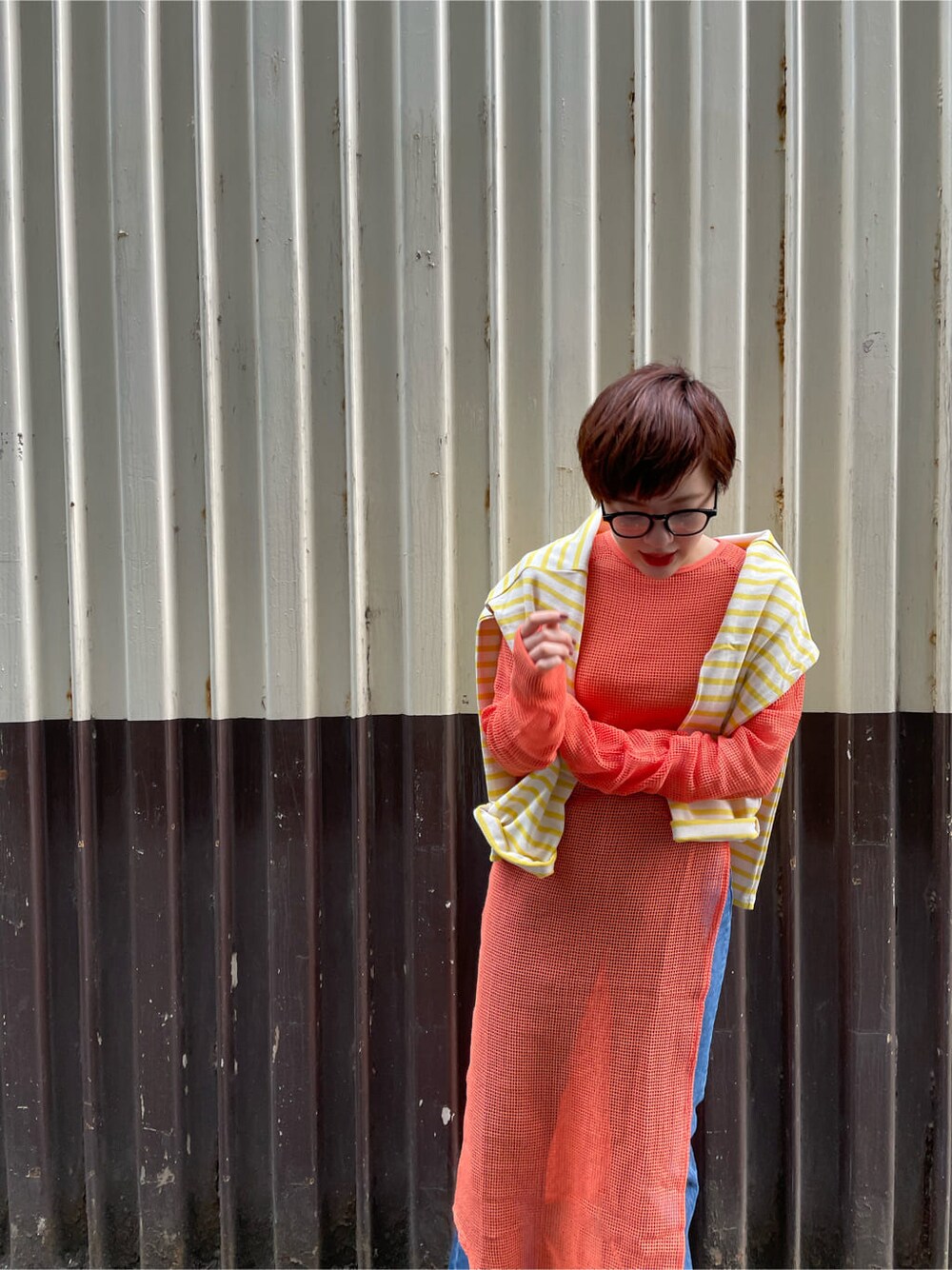 ブルー系のデニムパンツ、オレンジ系のワンピースを着用したレディースの春コーディネートの2枚目の写真