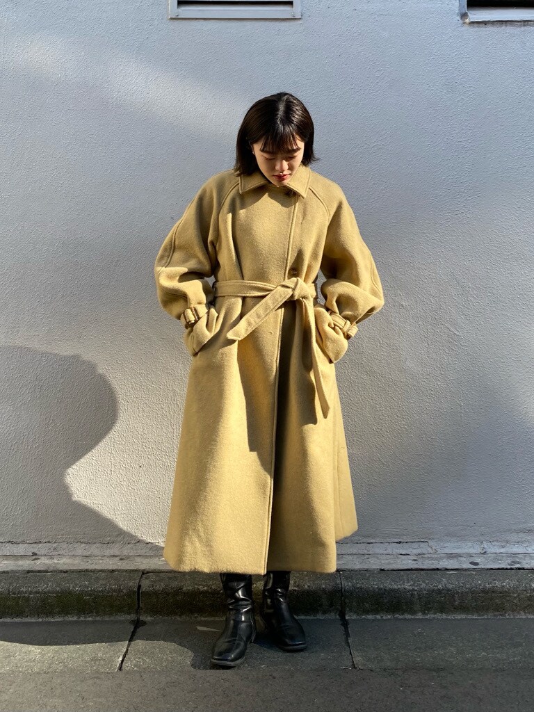 イエロー系のステンカラーコートを着用したレディースの冬コーディネートの5枚目の写真